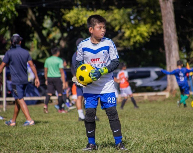 a kid a soccer goalkeeper holding a ball after a great save using 416 soccer goalkeeper training technique .