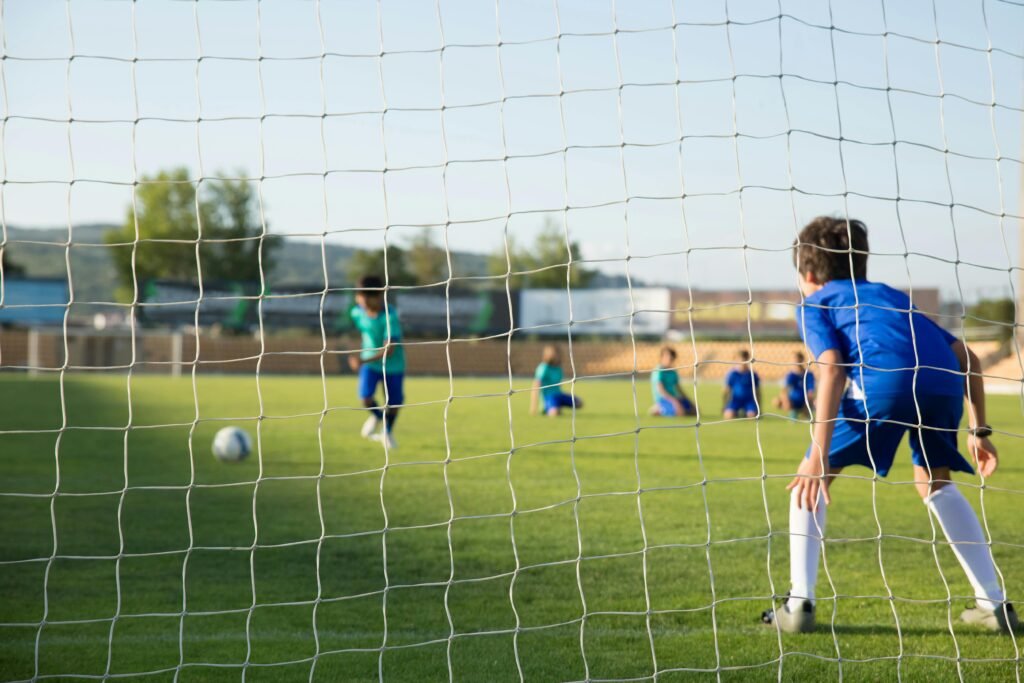a kid practicing goalkeeper trying to catch a panalty shoot during goalkeeper training at 416 soccer club . 